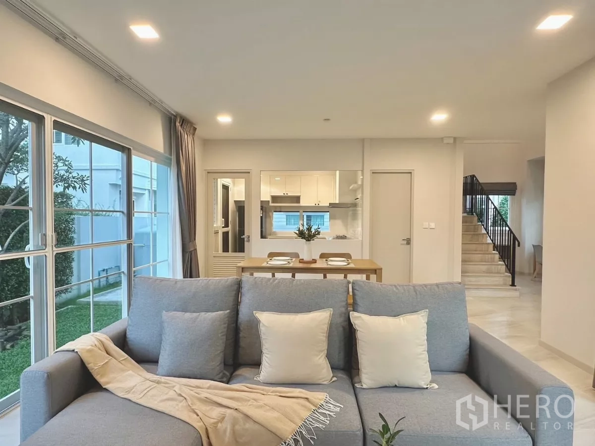 独立式住宅 出租在Bang Phli, Samut Prakan - 客厅视角望向厨房、餐桌与楼梯，采光充沛。