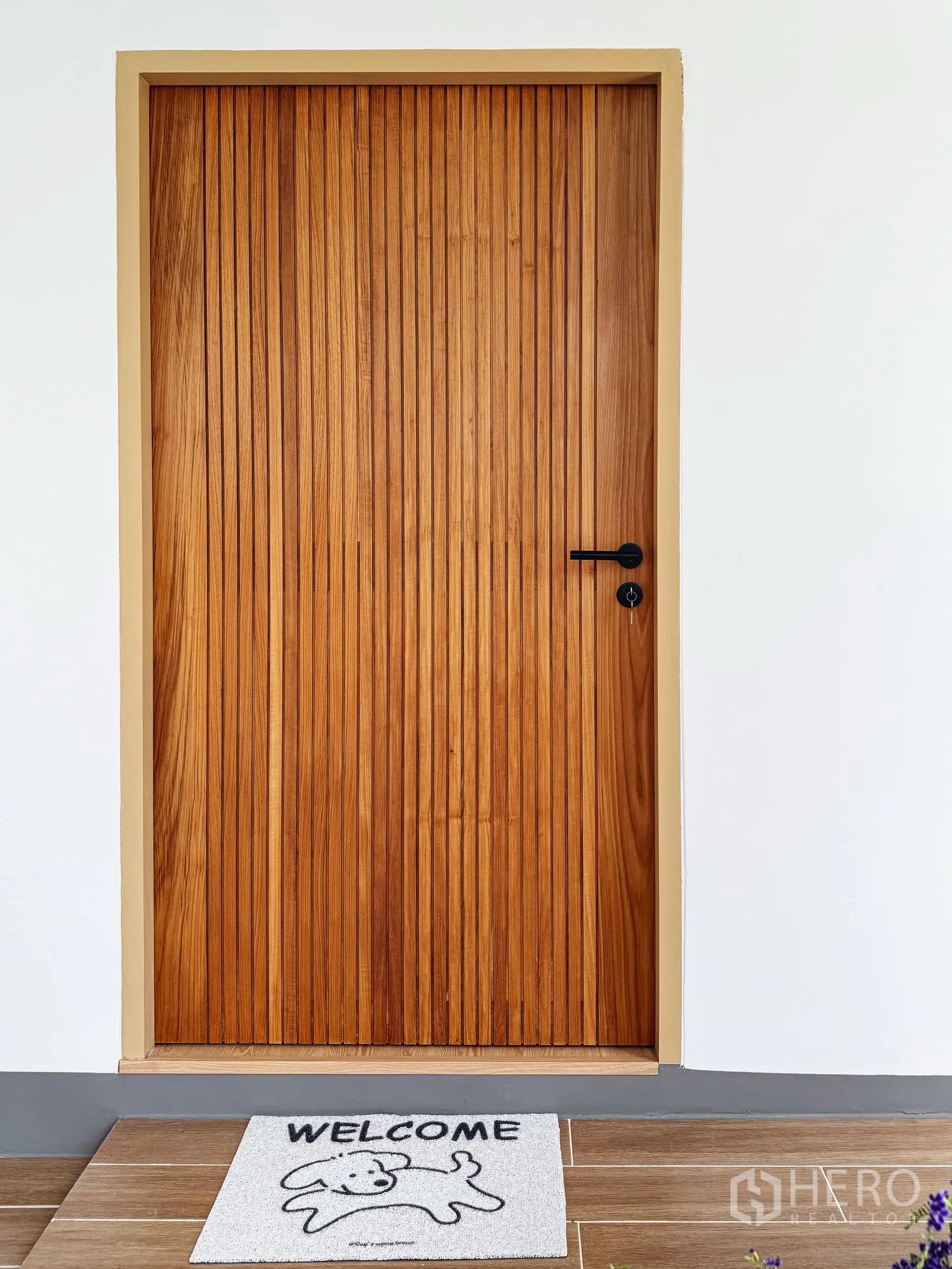 独立式住宅 出售在Suan Luang, Bangkok - 竖向木格栅入户门特写，脚垫写有欢迎字样。