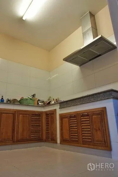 独立式住宅 出租或出售在Pak Kret, Nonthaburi - 独立泰式厨房，木质地柜、瓷砖墙面与不锈钢抽油烟机。