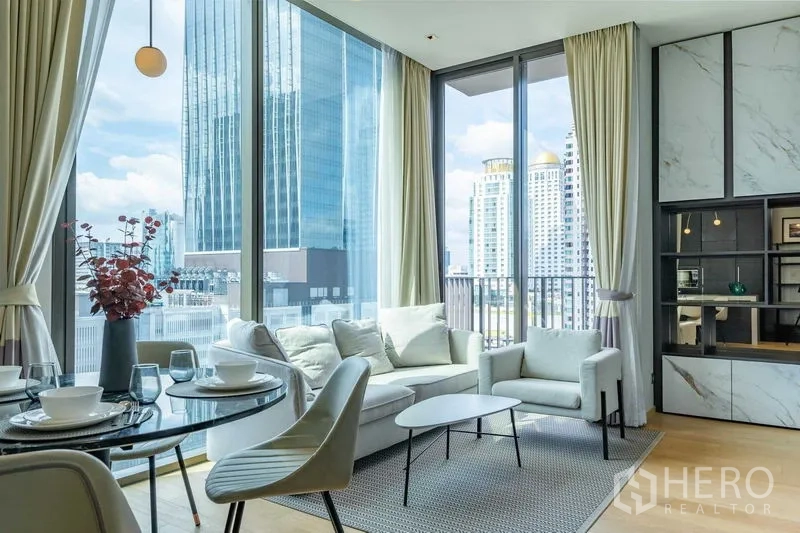 Condominium for rent - Bright living room with floor-to-ceiling windows, city skyline view, sofa and round dining table.