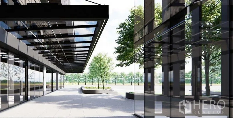 零售空间 出租在Khlong Toei, Bangkok - 现代玻璃立面与带雨棚的人行廊道，前方景观广场与行道树。