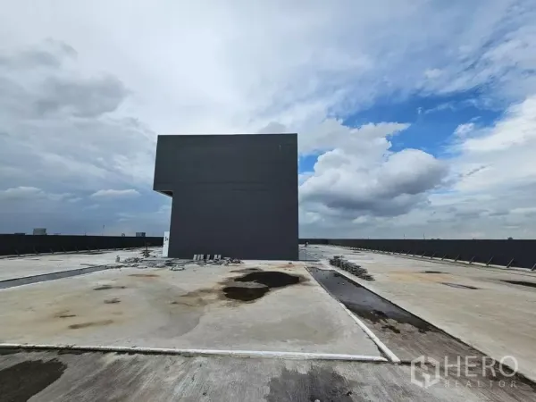 零售空间 出租 - 开阔屋顶平台，周边女儿墙与中央机电核心，云层密布。