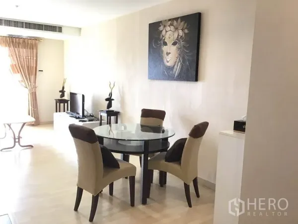 公寓 出租在Watthana, Bangkok - 采光充足的餐区，圆形玻璃餐桌与四把软包椅，浅色木地板，墙面装饰画与窗边电视柜。