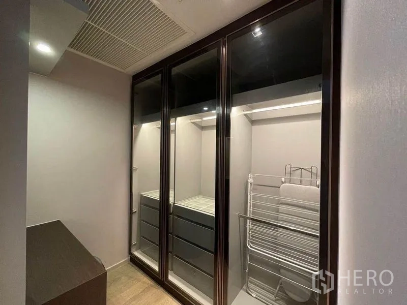 Condominium for rent in Bang Rak, Bangkok - Walk-in closet with illuminated glass wardrobes and built-in drawers.