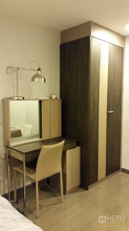 คอนโด ให้เช่าในWatthana, Bangkok - มุมห้องนอนพร้อมตู้เสื้อผ้าไม้ โต๊ะเครื่องแป้งกระจก และโคมไฟ พื้นลายไม้โทนอุ่น