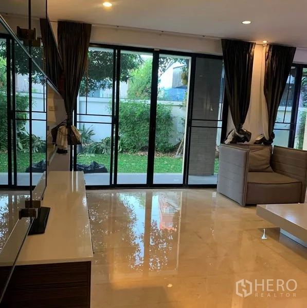 Detached House for rent in Din Daeng, Bangkok - Living area with full-height sliding glass doors opening to a lawn and patio.