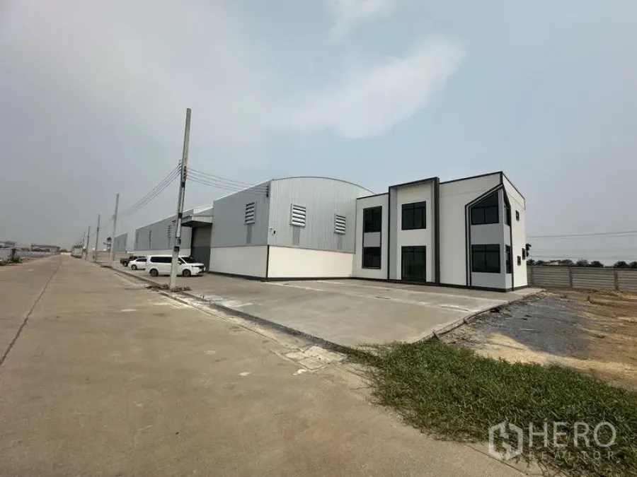 工厂 出租或出售在Sai Noi, Nonthaburi - 工厂与办公楼侧视，展示宽敞卡车通行广场与围栏。
