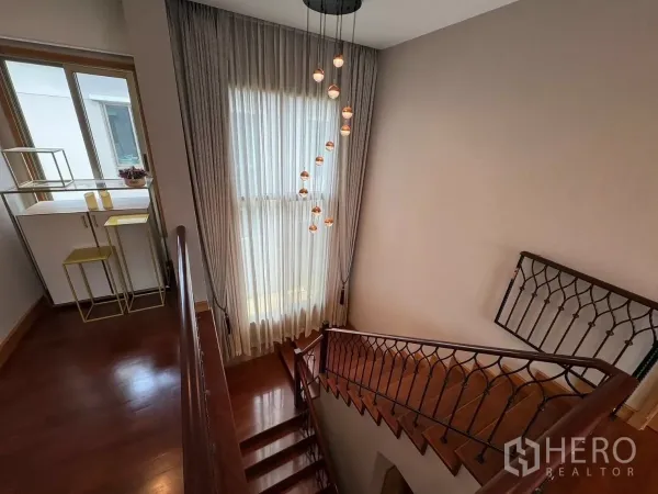 Detached House for rent in Prawet, Bangkok - Stair landing with tall window, sheer curtains and cascading pendant lights.