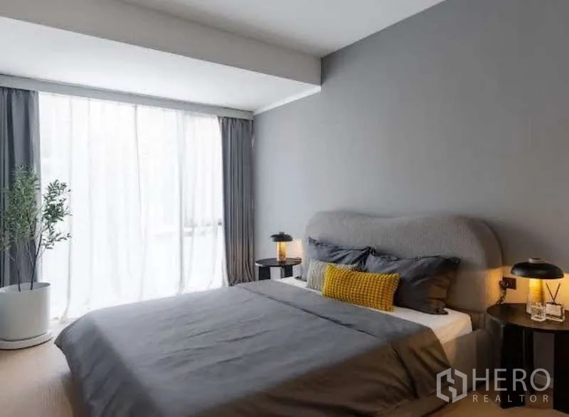 Townhouse for sale in Sathon, Bangkok - Secondary bedroom with grey feature wall, sheer curtains and soft natural light.