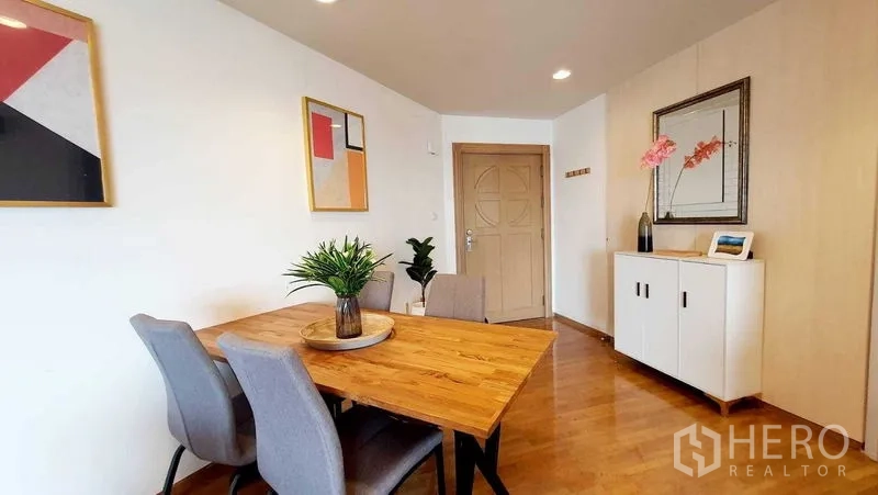 Condominium for sale in Bang Kho Laem, Bangkok - Dining area with wooden table, four chairs, console cabinet and modern art.