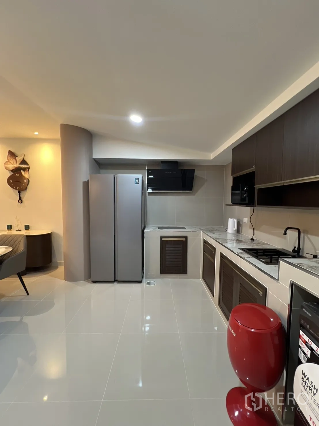 Townhouse for rent in Bang Phli, Samut Prakan - Contemporary kitchen with dark cabinets, cooktop, hood and a double-door refrigerator.