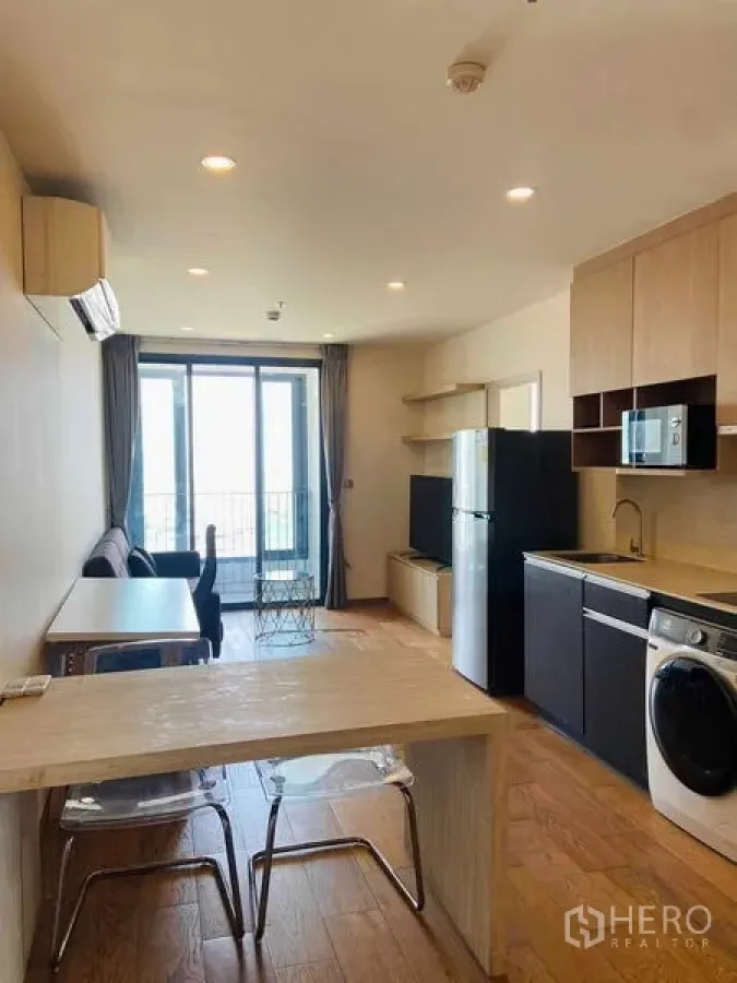 Condominium for rent or sale in Ratchathewi, Bangkok - Dining peninsula and kitchenette leading to a balcony with city outlook.