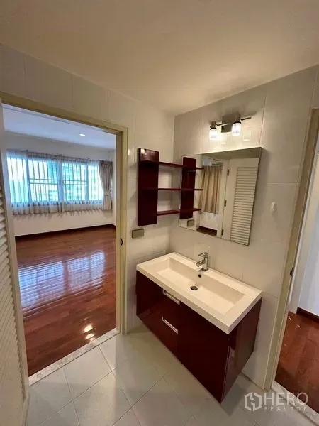 公寓 出租在Bangkok - 卧室与浴室之间的梳洗台，带置物架与现代灯光