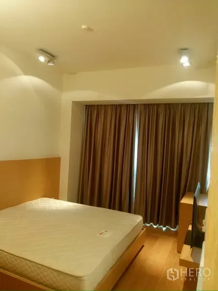 Condominium for rent in Sathon, Bangkok - Cozy bedroom with double bed, warm lighting and full-length blackout curtains.