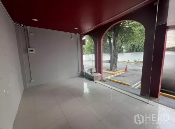 Retail Space for rent in Watthana, Bangkok - Interior view through floor-to-ceiling glass looking out to parking area and trees.