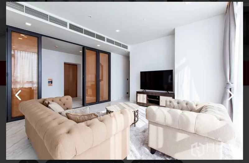 คอนโด ให้เช่าหรือขายในWatthana, Bangkok - ห้องนั่งเล่นสว่าง โซฟาบุหนังสีเบจ ตู้ทีวี และประตูกระจกบานเลื่อน