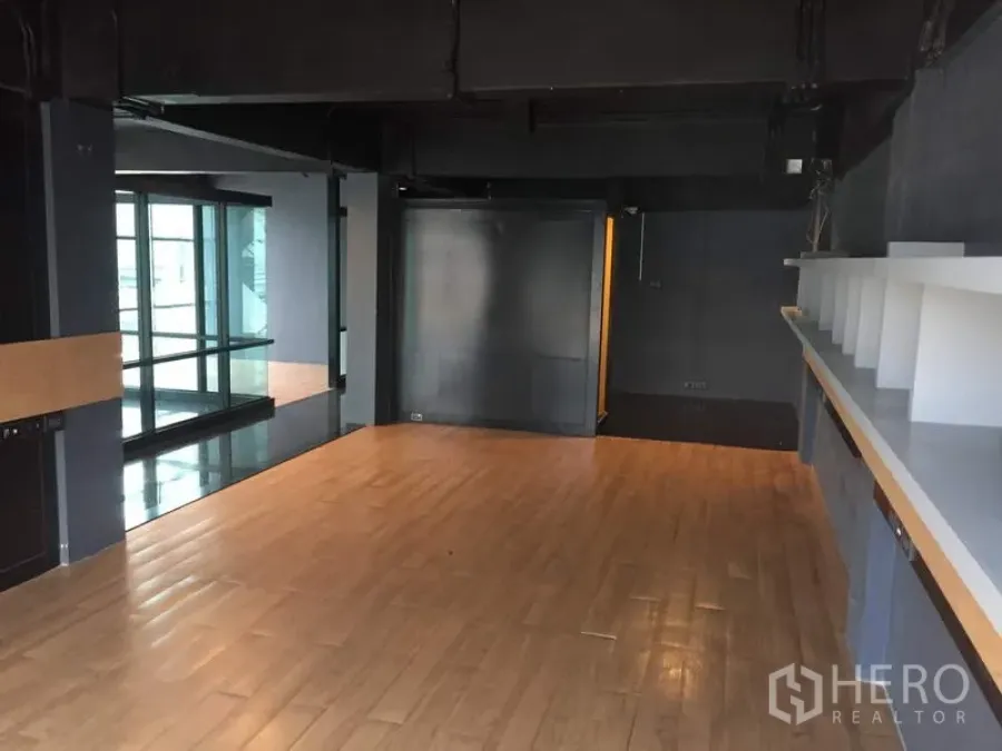 零售空间 出租在Khlong Toei, Bangkok - 开放式零售空间，木地板、深色工业风天花、内置展示架与玻璃隔墙。