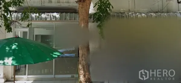 Retail Space for rent in Bang Rak, Bangkok - Glass-fronted shop entrance with sliding doors, shaded sidewalk, a roadside tree and a green umbrella along a retail row in Bang Rak.