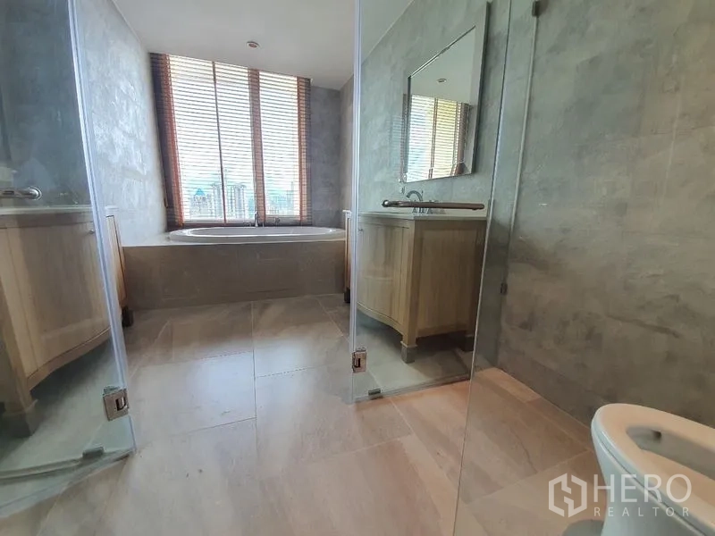 คอนโด ขาย - ห้องน้ำปูกระเบื้องหิน มีฝักบัวกระจกใส และอ่างอาบน้ำติดหน้าต่าง