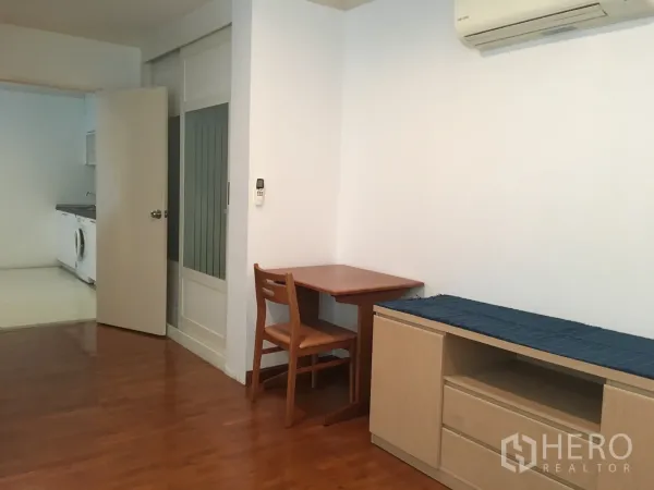 Condominium for rent or sale in Watthana, Bangkok - Compact dining and work nook with wooden table and chair, built-in storage and sliding door.