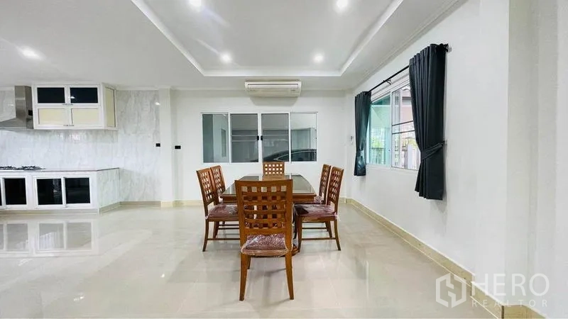 Detached House for rent in Bang Kapi, Bangkok - Dining corner with wooden table and four chairs beside windows and air conditioning.