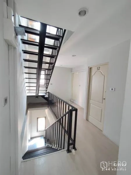 零售空间 出租在Phaya Thai, Bangkok - 明亮楼梯平台，黑色栏杆、白色房门与自然采光。