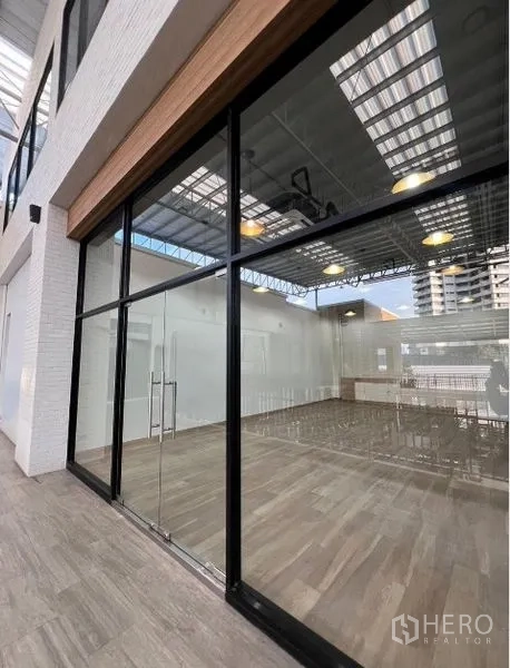 零售空间 出租 - 临街零售铺面，整面落地玻璃与木纹砖地面，外侧为有顶步行通道。