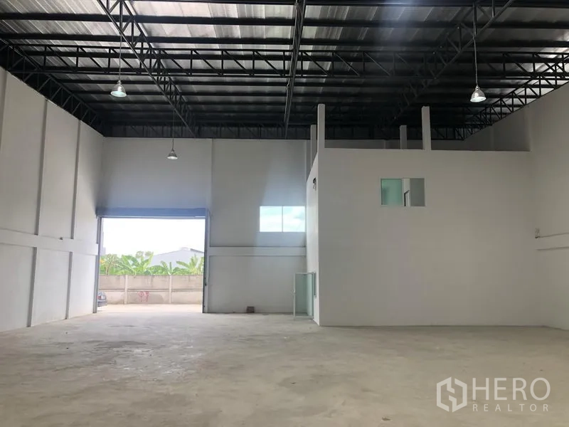 工厂 出租在Sai Noi, Nonthaburi - 仓库内部设宽卷帘门、夹层办公模块与混凝土地坪。