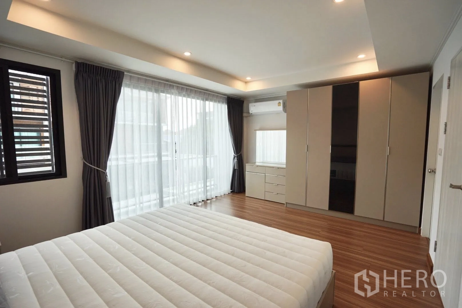 Townhouse for rent in Bang Kapi, Bangkok - Bedroom with large wardrobes, dresser and wide windows with sheer curtains for natural light.