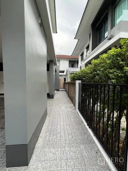Detached House for rent in Bang Kapi, Bangkok - Side walkway along the house with fence and shrubs.