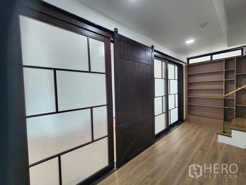 带办公室的家 出租在Prawet, Bangkok - 走廊设置谷仓式推拉门与磨砂玻璃面板，旁侧为内建书架。