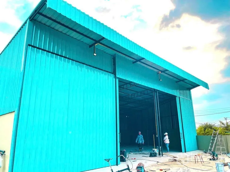 Warehouse for rent in Sai Mai, Bangkok - Close exterior view of tall teal sliding doors on the warehouse facade.