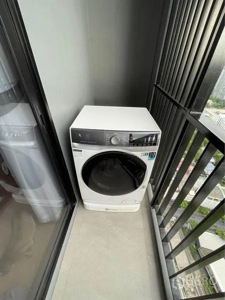 Condominium for rent in Watthana, Bangkok - Washing machine on a narrow balcony with safety railing and city outlook.