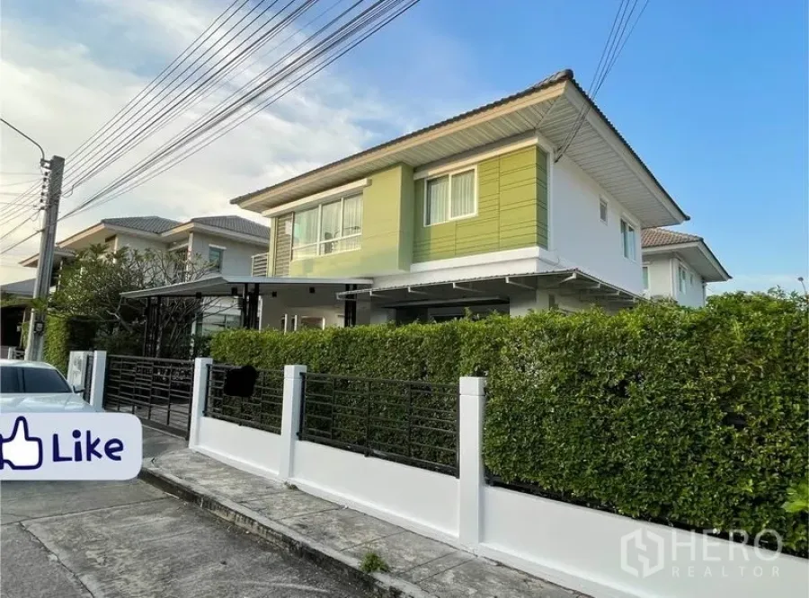 Detached House for sale in Khlong Toei, Bangkok - Street view of modern green-and-white house with hedge fence and wide eaves.