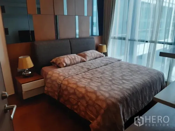 คอนโด ให้เช่าในWatthana, Bangkok - ห้องนอนอบอุ่น หัวเตียงบุผ้า โต๊ะข้างเตียง และหน้าต่างกระจกสูงจรดเพดานพร้อมม่านโปร่ง