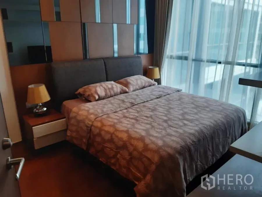 คอนโด ให้เช่าในWatthana, Bangkok - ห้องนอนอบอุ่น หัวเตียงบุผ้า โต๊ะข้างเตียง และหน้าต่างกระจกสูงจรดเพดานพร้อมม่านโปร่ง