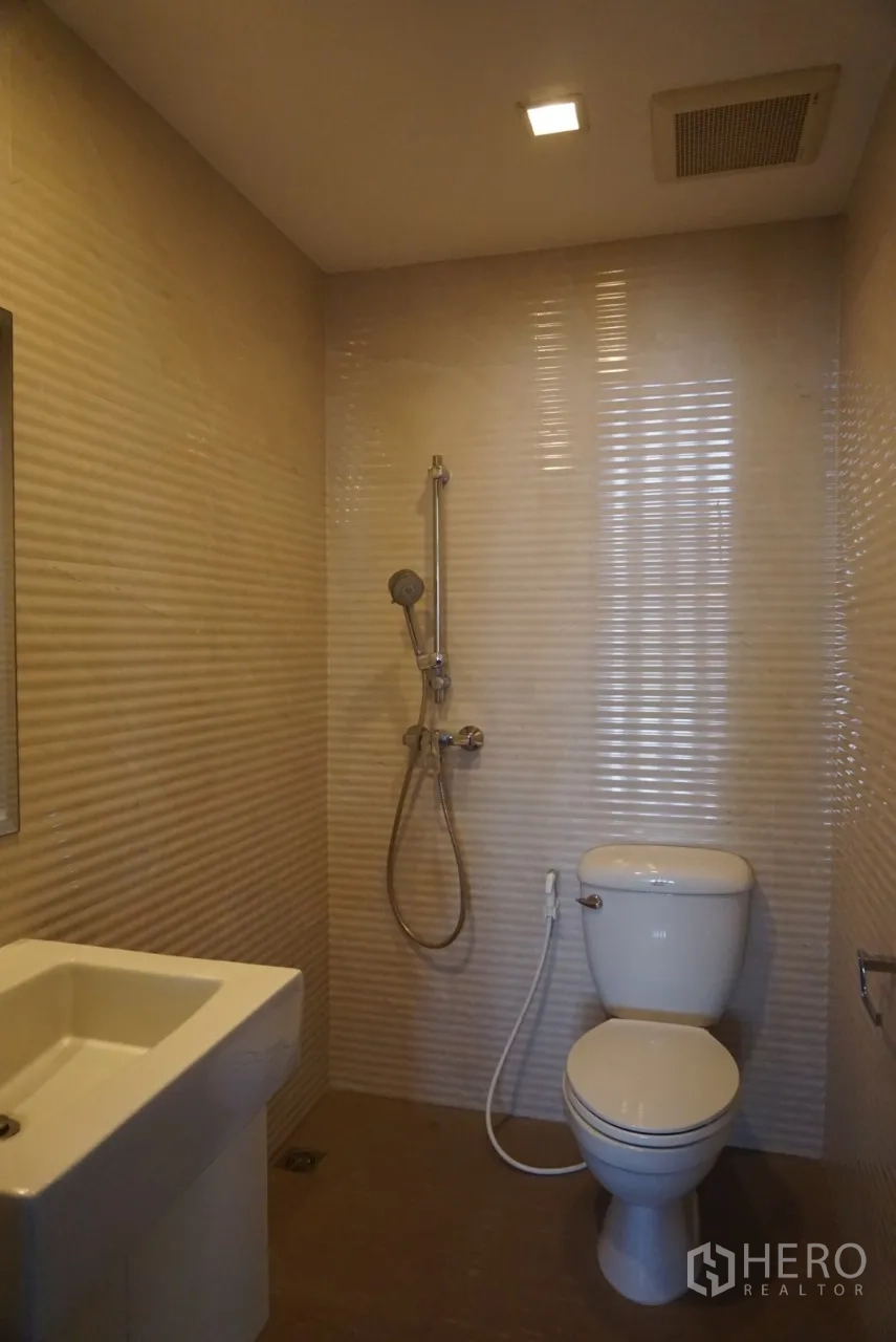 คอนโด ให้เช่าในWatthana, Bangkok - ห้องน้ำปูกระเบื้องลายเส้นสีเบจ พร้อมฝักบัวสายอ่อนและโถสุขภัณฑ์