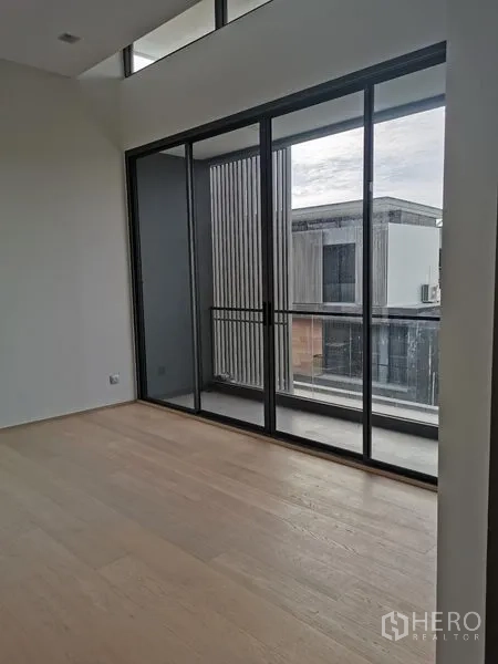 Detached House for sale in Wang Thonglang, Bangkok - Unfurnished bedroom with wood flooring and floor-to-ceiling sliding doors opening to a balcony.