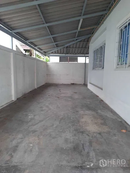 Home Office for rent in Watthana, Bangkok - Covered carport with concrete floor and barred windows.