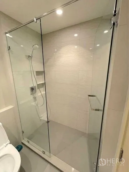 Condominium for rent in Watthana, Bangkok - Modern bathroom with glass-enclosed shower and wall-mounted showerhead.