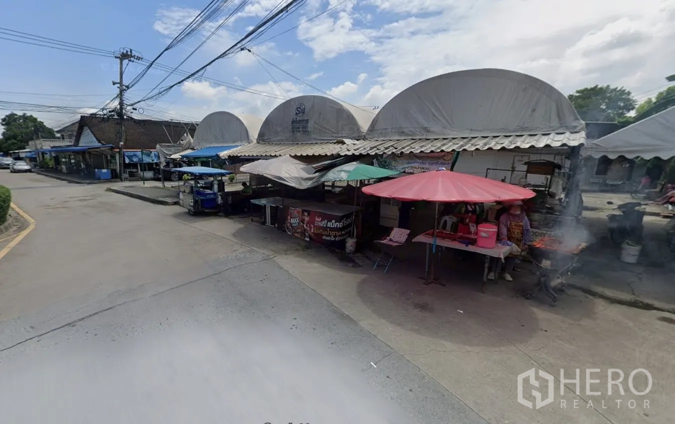 Land for rent in Bang Kapi, Bangkok - Market stalls with umbrellas along the edge of the land beside the road.