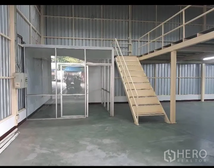 Warehouse for rent in Bang Kho Laem, Bangkok - Warehouse interior with glass-partitioned office and metal staircase leading to a mezzanine.