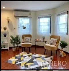 独立式住宅 出租在Phra Khanong, Bangkok - 舒适角落客厅，两把扶手椅，几何地毯与陈列架和窗户。