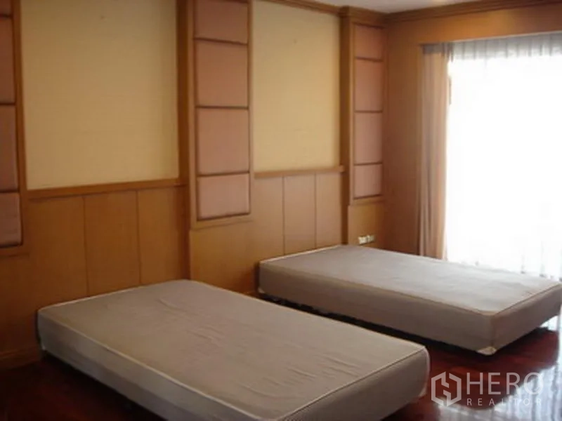 อพาร์ทเมนท์ ให้เช่าในKhlong Toei, Bangkok - ห้องนอนผนังไม้ พร้อมที่นอนเดี่ยวสองเตียงและหน้าต่างสูงจรดเพดาน