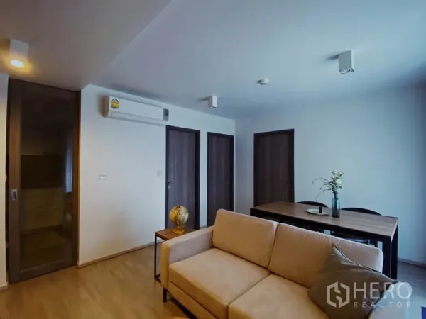 คอนโด ให้เช่าในPathum Wan, Bangkok - มุมห้องนั่งเล่นเห็นประตูไม้สามบาน เครื่องปรับอากาศ และโต๊ะทานอาหาร