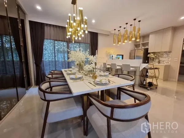 Detached House for rent in Prawet, Bangkok - Elegant dining area with marble table, gold chandeliers and open kitchen with island.