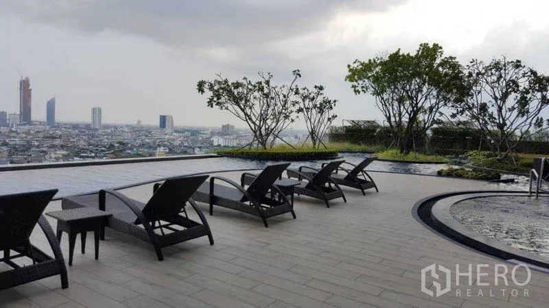 Condominium for rent in Bang Kho Laem, Bangkok - Expansive pool terrace with loungers, trees, and city views.