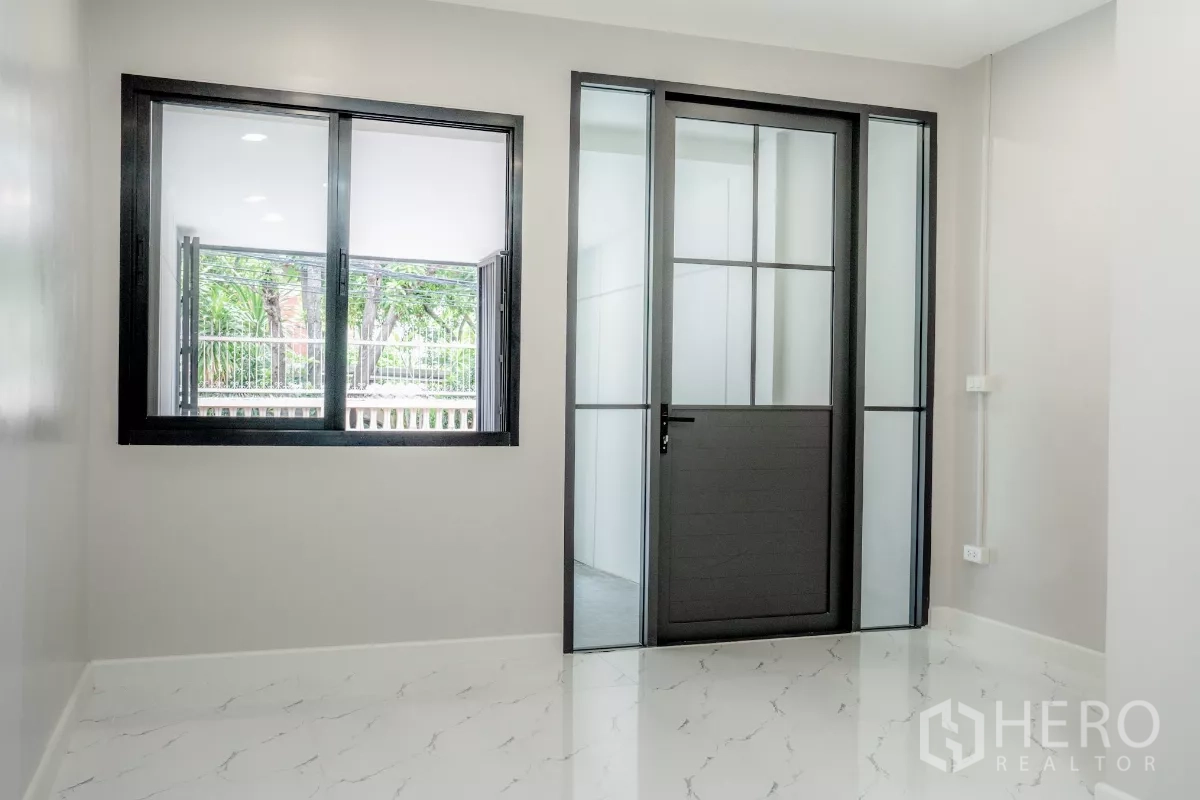 ทาวน์เฮาส์ ขายในWatthana, Bangkok - ห้องอเนกประสงค์ชั้นล่างพร้อมหน้าต่าง และประตูกระจกกรอบดำ
