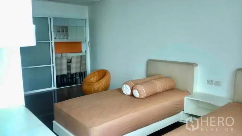 Condominium for sale in Bang Rak, Bangkok - Second bedroom with twin beds, wicker chair and sliding glass door to the dining area.