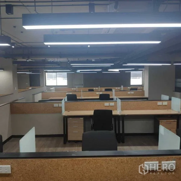 办公空间 出租 - 成排卡座在吊装灯带下，尽头有窗户采光。